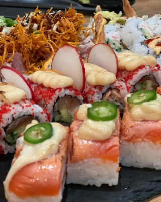 Pressed aburi sushi on slate — flame-seared salmon with jalapeño, radish and crisp fried shallots.