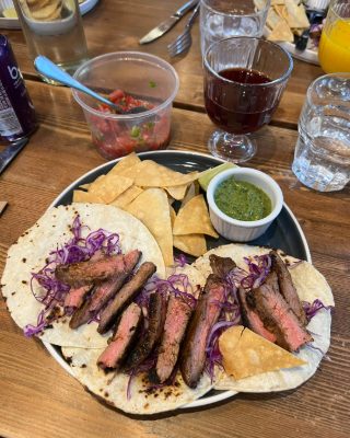Steak tacos on a plate with purple cabbage, tortilla chips and salsa verde, made in a cooking class.